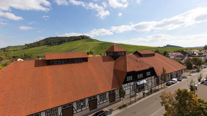 Die Alte Kelter in Fellbach mit rotem Ziegeldach und Fachwerk, umgeben von gr&uuml;nen Weinbergen und blauem Himmel., &copy; Achim Mende