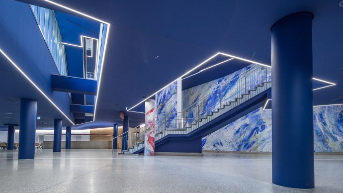 Modernes Foyer mit blauen Säulen, Treppe und abstrakter Wandkunst. Helle Beleuchtung und glatte Böden schaffen eine elegante Atmosphäre., © Kultur- und Kongresszentrum Liederhalle, Florian Selig