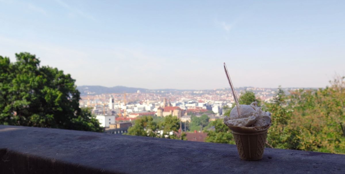 Ein Eisbecher steht auf einer Mauer mit Blick auf die Stadt Stuttgart vom Eugensplatz aus. Im Hintergrund sind Bäume und Gebäude zu sehen., © Stuttgart-Marketing GmbH