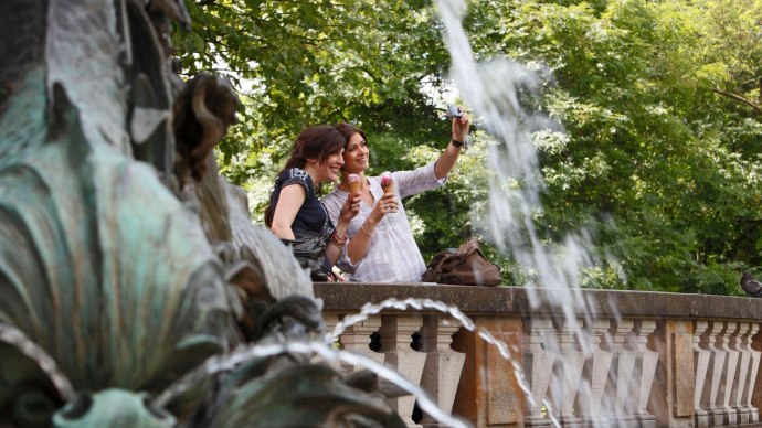 Zwei Frauen machen ein Selfie am Galateabrunnen, halten Eis in der Hand. Im Hintergrund sind Bäume und ein Wasserspritzer zu sehen., © Stuttgart-Marketing GmbH Christoph Düpper Zwei Frauen machen ein Selfie am Galateabrunnen, halten Eis in der Hand. Im Hintergrund sind Bäume und ein Wasserspritzer zu sehen., © Stuttgart-Marketing GmbH Christoph Düpper