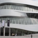 The Mercedes-Benz Museum in Stuttgart shows off its modern, curved architecture with a glass façade and several flags in front of it., © Stuttgart-Marketing GmbH