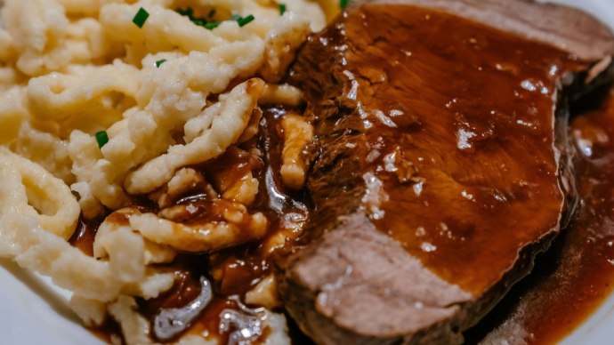 Ein Teller mit Spätzle und einem Stück Braten, übergossen mit dunkler Soße. Die Spätzle sind mit Schnittlauch garniert., © Thomas Niedermüller