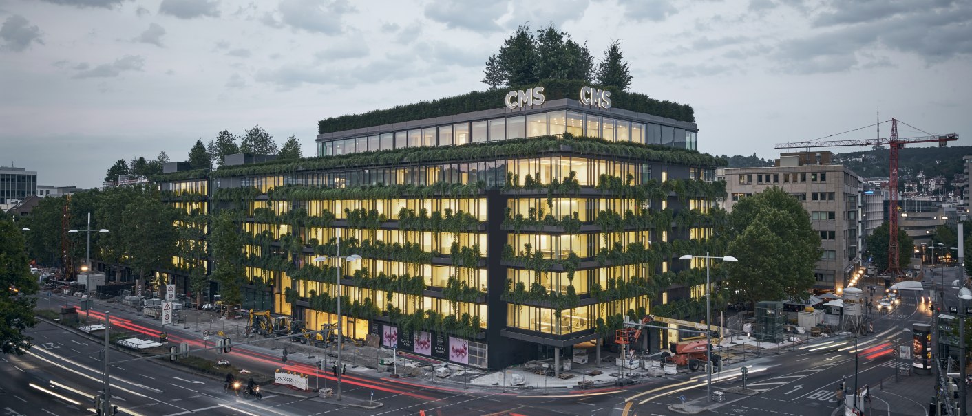 Begrüntes Gebäude in der Stadt bei Dämmerung, beleuchtete Fenster, Straßenverkehr mit Lichtspuren, Wolken am Himmel., © Ferdinand Piëch Holding GmbH