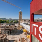 Construction site in Stuttgart with a tower and a red building in the foreground. A crane and construction work are visible, blue sky in the background., © Thomas Niedermüller