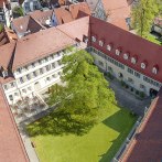Aerial view of the inner courtyard of Urach Abbey with red roofs, a large tree and surrounding buildings., © Claus Arnold