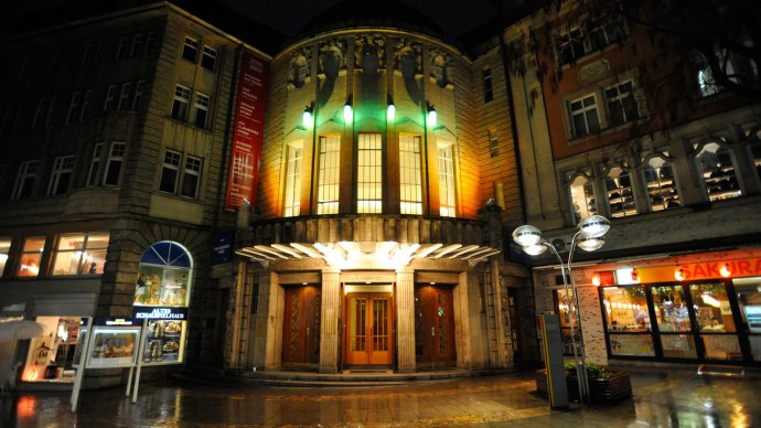 Eingang des Alten Schauspielhauses bei Nacht, beleuchtet mit bunten Lichtern. Die Fassade ist von historischen Geb&auml;uden umgeben., &copy; Schauspielb&uuml;hnen Stuttgart