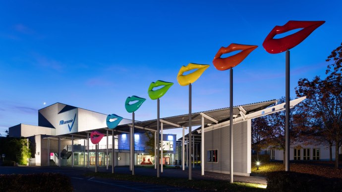 The FILharmonie at dusk, with colorful lip sculptures on high poles in front of the building., &copy; Filharmonie_gf