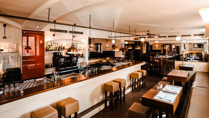 Ein stilvolles Restaurant mit Bar, Holzm&ouml;beln und moderner Beleuchtung. Die Bar ist gut best&uuml;ckt, und es gibt Sitzgelegenheiten mit gedeckten Tischen., &copy; Amadeus