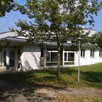Modernes Gebäude mit weißen Wänden und großen Fenstern, umgeben von Bäumen und Rasen im Kulturzentrum Baltmannsweiler., © GemeindeBaltmannsweiler_GF