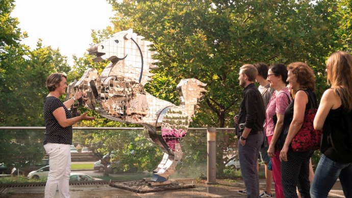 Eine Gruppe von Menschen betrachtet eine glänzende, spiegelnde Pferdeskulptur im Freien, umgeben von Bäumen., © Stuttgart-Marketing GmbH
