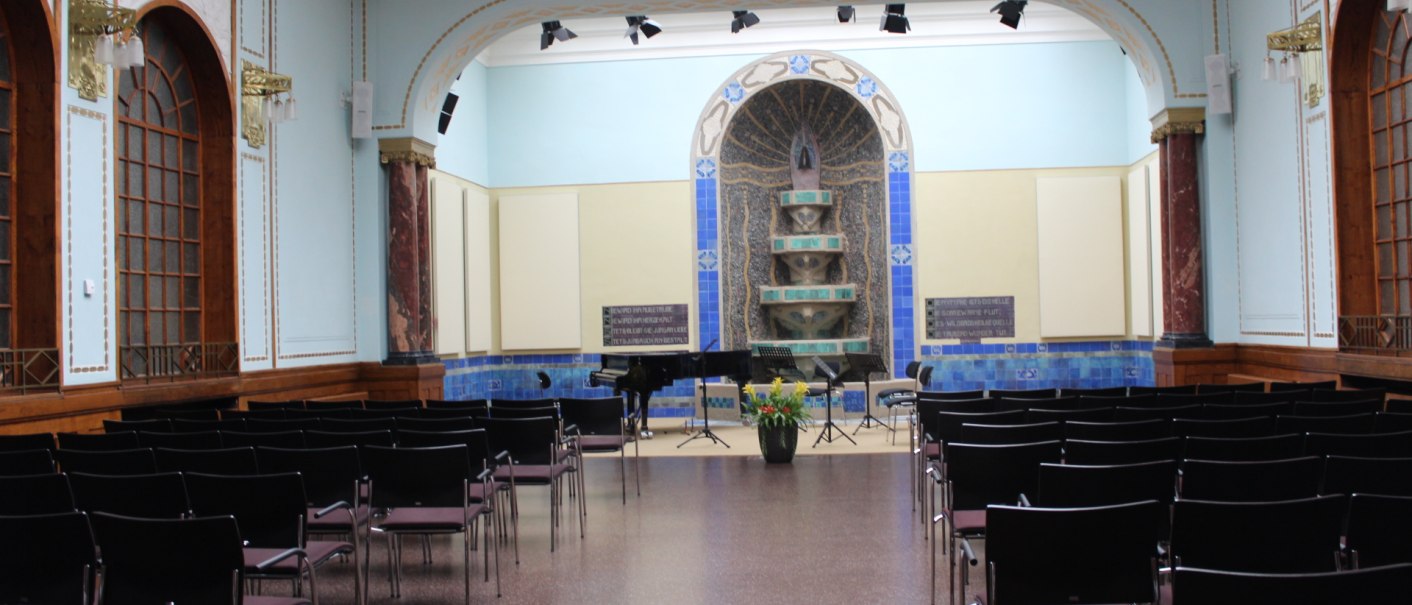 An elegant room with rows of chairs, a grand piano and a decorative blue wall. The room has high ceilings and large windows., © Forum Koenig-Karls-Bad An elegant room with rows of chairs, a grand piano and a decorative blue wall. The room has high ceilings and large windows., © Forum Koenig-Karls-Bad