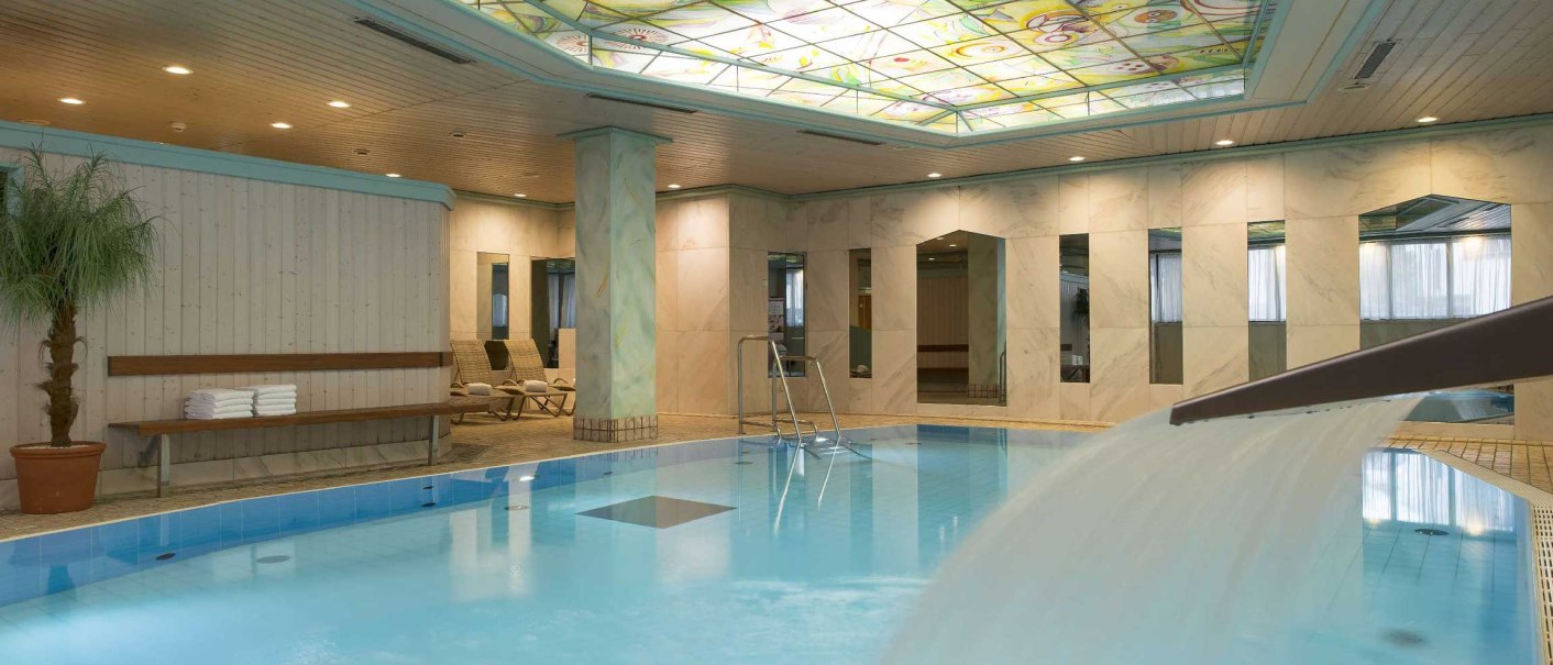 Swimming pool at the Maritim Hotel Stuttgart with waterfall, sun loungers and colorful ceiling. Elegant atmosphere with marble walls and plants., © Maritim Hotelgesellschaft mbH Swimming pool at the Maritim Hotel Stuttgart with waterfall, sun loungers and colorful ceiling. Elegant atmosphere with marble walls and plants., © Maritim Hotelgesellschaft mbH