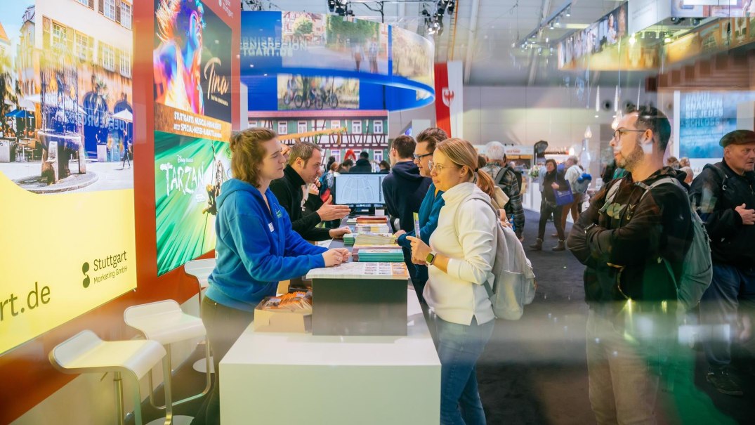 Besucher an einem Messestand auf der CMT Messe 2025 in Stuttgart, mit bunten Werbeplakaten im Hintergrund., &copy; Stuttgart-Marketing GmbH, Thomas Niederm&uuml;ller