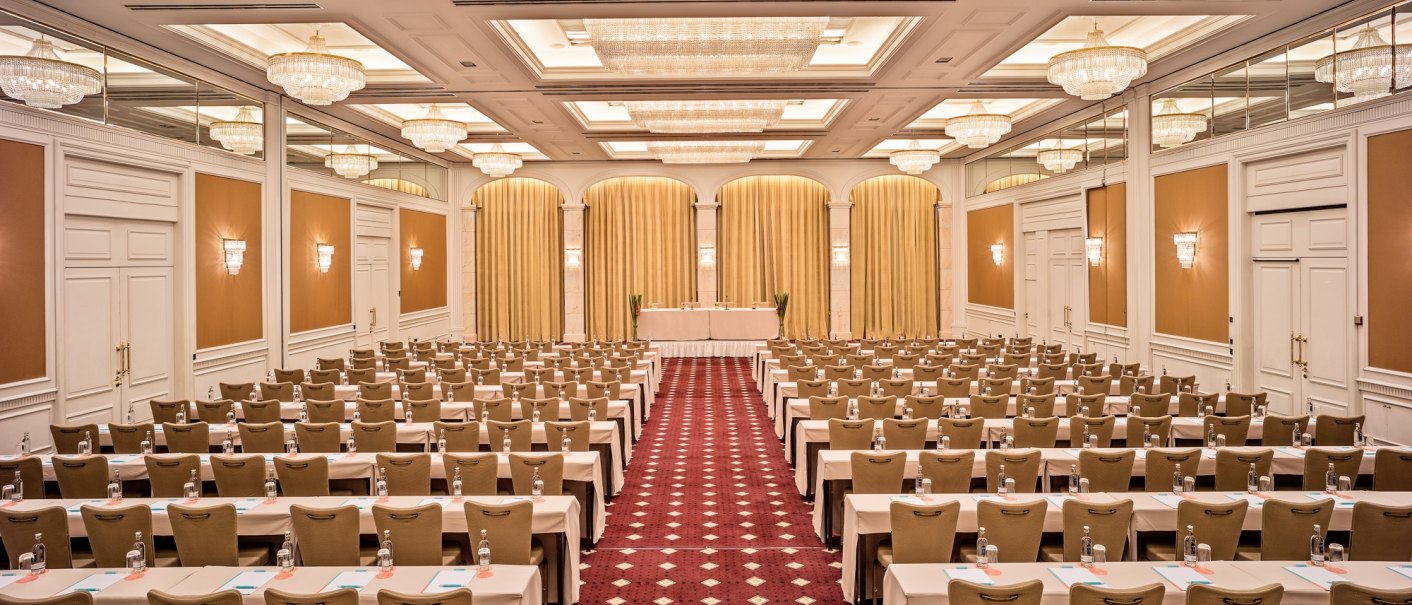 Eleganter Konferenzraum mit Kronleuchtern, roten Teppich und Reihen von Tischen und St&uuml;hlen im Le M&eacute;ridien Stuttgart, Raum Elysee., &copy; Le M&eacute;ridien Stuttgart, Gerrit Meier