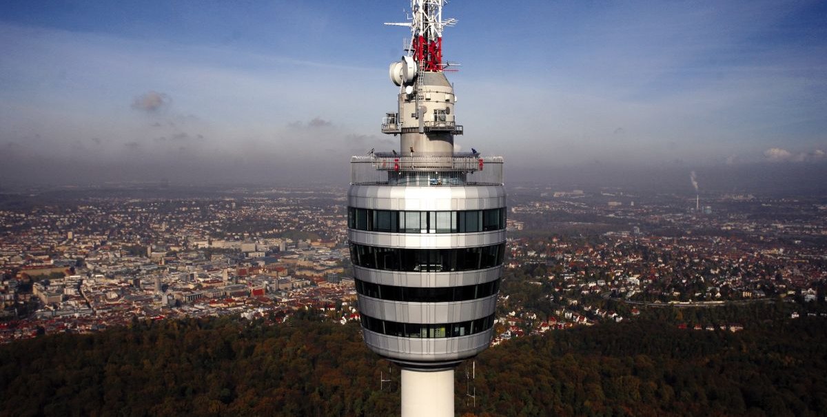 Der Fernsehturm Stuttgart ragt über die Stadtlandschaft, umgeben von bewaldeten Gebieten und urbanen Strukturen unter einem klaren blauen Himmel., © Stuttgart-Marketing GmbH, Achim Mende Der Fernsehturm Stuttgart ragt über die Stadtlandschaft, umgeben von bewaldeten Gebieten und urbanen Strukturen unter einem klaren blauen Himmel., © Stuttgart-Marketing GmbH, Achim Mende