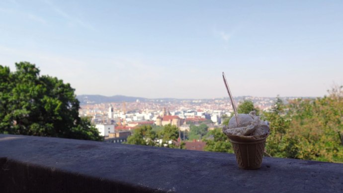 Ein Eisbecher steht auf einer Mauer mit Blick auf die Stadt Stuttgart vom Eugensplatz aus. Im Hintergrund sind Bäume und Gebäude zu sehen., © Stuttgart-Marketing GmbH Ein Eisbecher steht auf einer Mauer mit Blick auf die Stadt Stuttgart vom Eugensplatz aus. Im Hintergrund sind Bäume und Gebäude zu sehen., © Stuttgart-Marketing GmbH