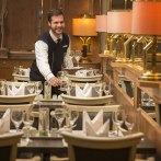 A waiter in the restaurant of the Maritim Hotel Stuttgart sets tables with glasses and napkins. Elegant furnishings with warm light., © Jesco Birkhahn
