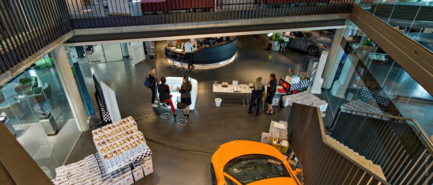 Foyer of the V8 HOTEL MOTORWORLD Region Stuttgart with visitors, cars and information stands. Modern architecture with glass walls and stairs., &copy; Hardy Mutschler