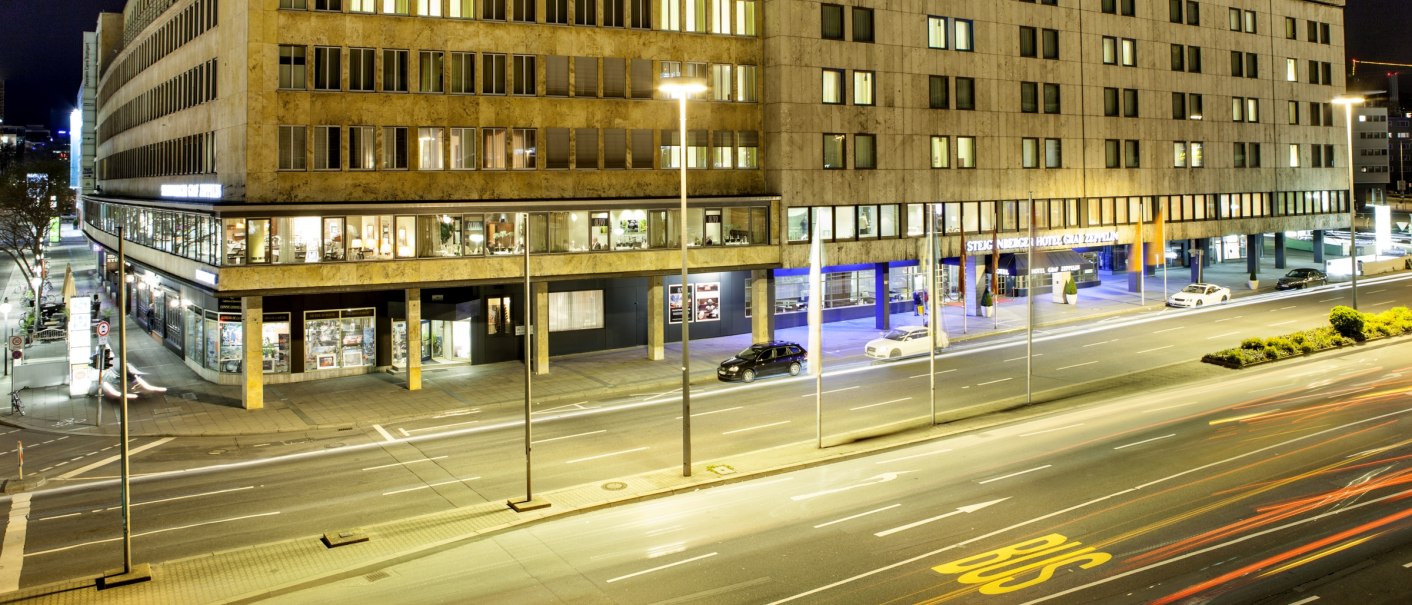 Nachtansicht des Steigenberger Graf Zeppelin Hotels in Stuttgart. Die beleuchtete Fassade zeigt mehrere Fenster und wehende Flaggen auf dem Dach., © Steigenberger Hotels AG, Tanja Ganzer Nachtansicht des Steigenberger Graf Zeppelin Hotels in Stuttgart. Die beleuchtete Fassade zeigt mehrere Fenster und wehende Flaggen auf dem Dach., © Steigenberger Hotels AG, Tanja Ganzer