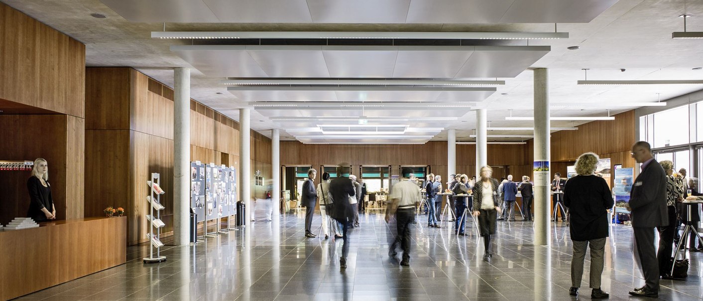 People in the foyer of the Kultur- und Kongresszentrum Kornwestheim, modern architecture with wood paneling and large windows., © © Brigida González, Stuttgart People in the foyer of the Kultur- und Kongresszentrum Kornwestheim, modern architecture with wood paneling and large windows., © © Brigida González, Stuttgart