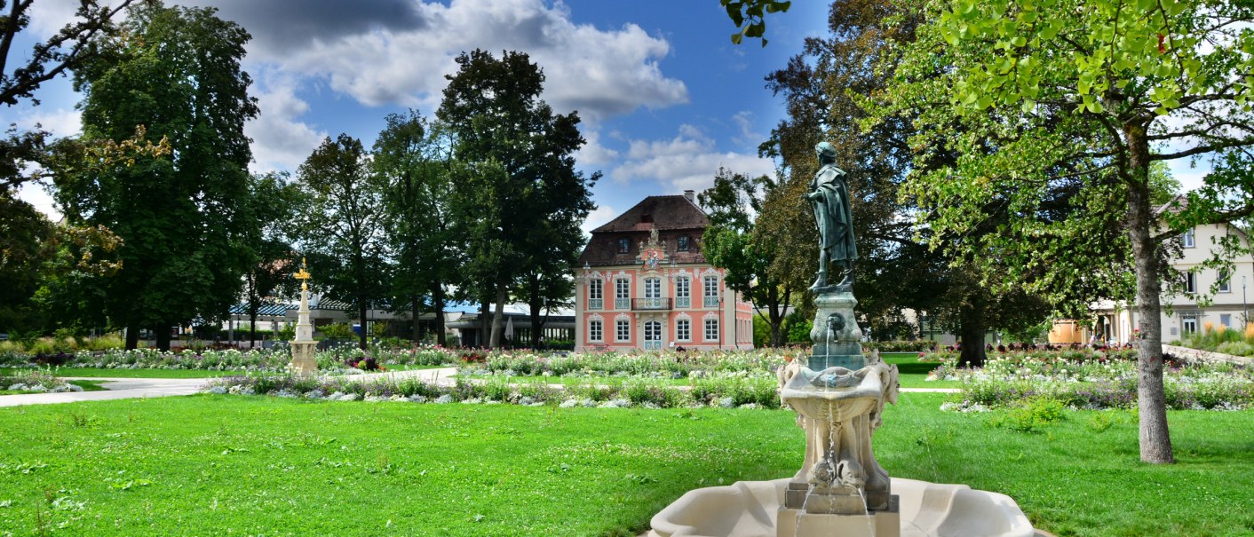 A rococo castle in a well-tended garden with a fountain in the foreground, surrounded by trees and flowering plants., © Congress-Centrum Stadtgarten Schwäbisch Gmünd