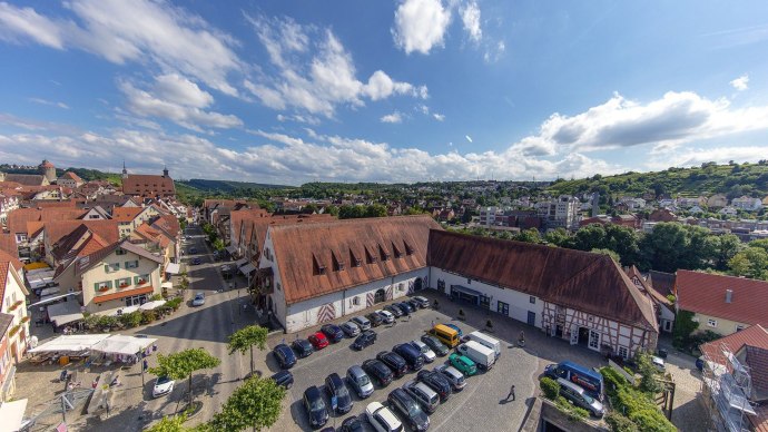 Luftaufnahme der Stadthalle Alte Kelter in Besigheim, umgeben von traditionellen Gebäuden und einem Parkplatz mit Autos. Im Hintergrund grüne Hügel., © Stadthalle Alte Kelter Besigheim_Achim Mende