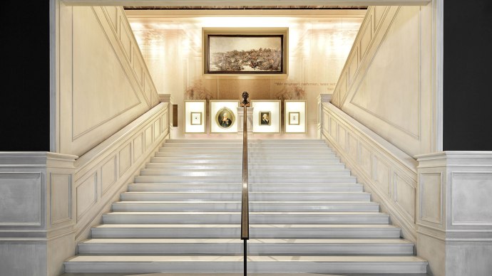 Eleganter Treppenaufgang im Haus der Geschichte Baden-Württemberg, dekoriert mit Gemälden und einer Büste an der Wand., © Daniel Stauch