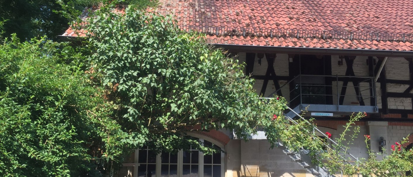 Half-timbered building with red tiled roof, surrounded by lush vegetation. A metal staircase leads to the upper floor., © FGA_GF Half-timbered building with red tiled roof, surrounded by lush vegetation. A metal staircase leads to the upper floor., © FGA_GF