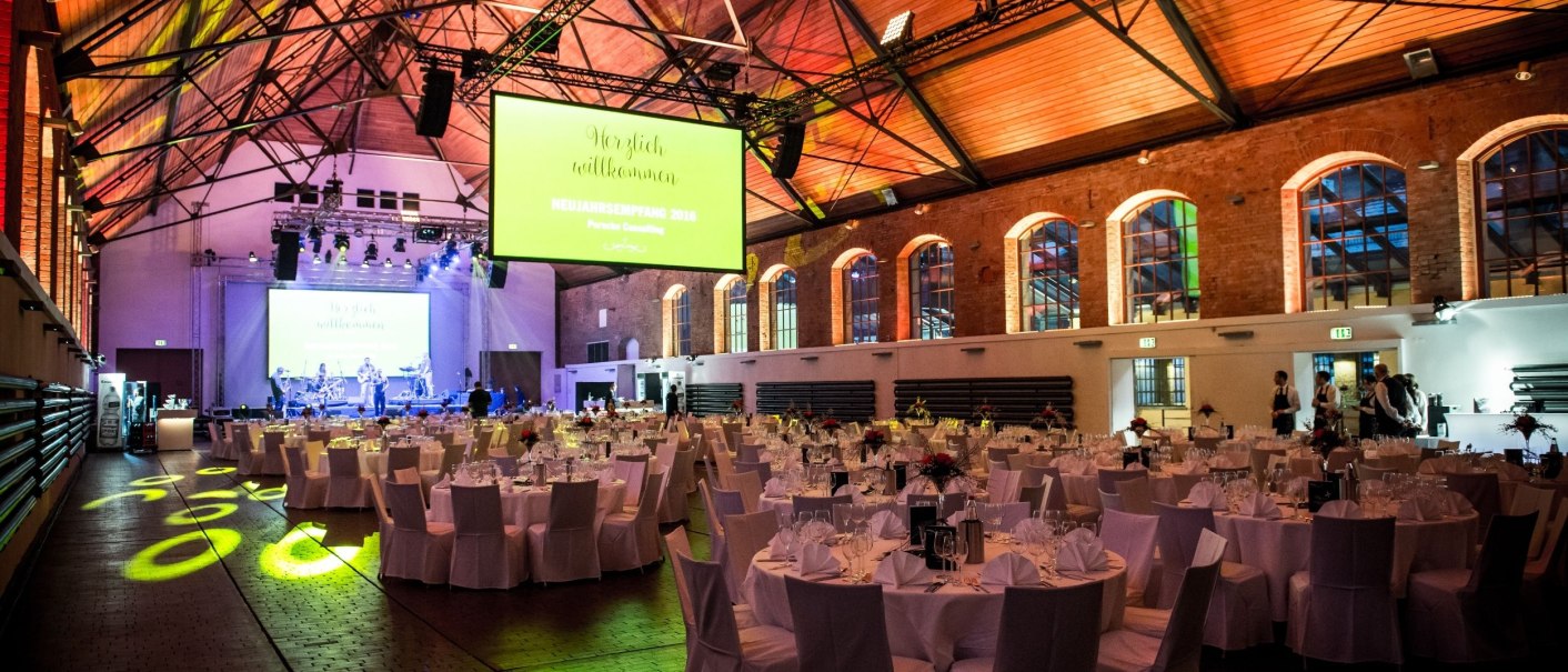 Die Phoenixhalle im Römerkastell ist festlich dekoriert mit runden, gedeckten Tischen und einer Bühne im Hintergrund., © Neon-Photography.com | Tobias Stoffels