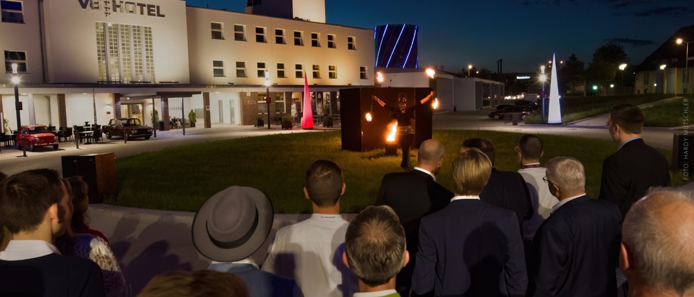 Nachtaufnahme des V8 Hotels in Stuttgart mit einer Feuershow vor einem Publikum im Freien., © Hardy Mutschler
