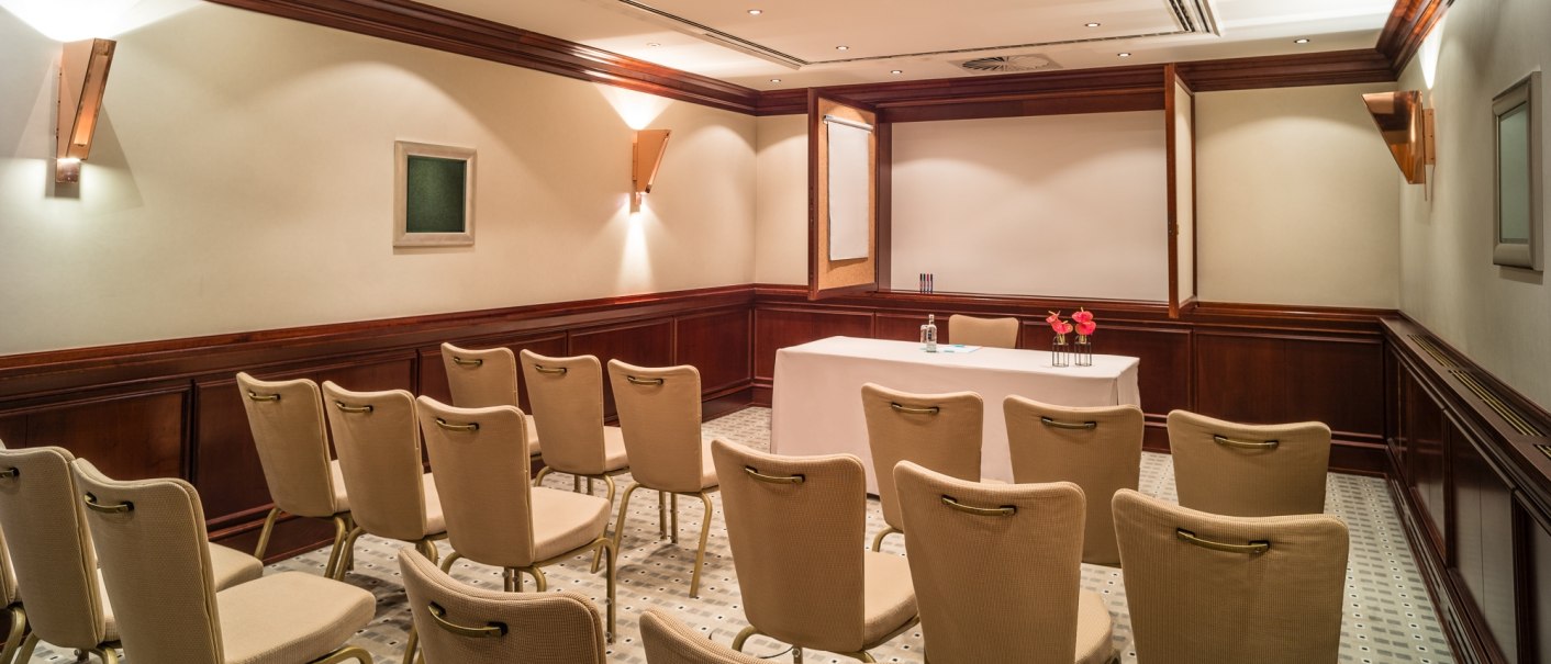 An elegant conference room at Le Méridien Stuttgart with beige chairs, a table with flowers and a screen on the wall., © Le Méridien Stuttgart An elegant conference room at Le Méridien Stuttgart with beige chairs, a table with flowers and a screen on the wall., © Le Méridien Stuttgart