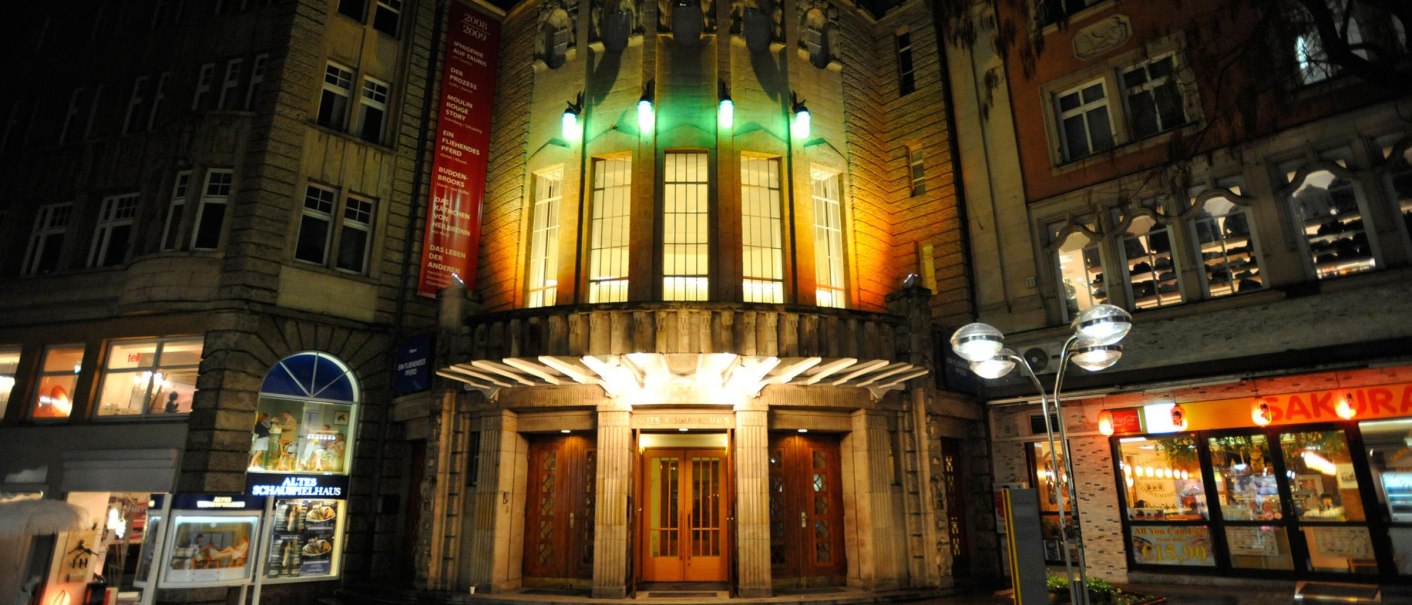 Eingang des Alten Schauspielhauses bei Nacht, beleuchtet mit bunten Lichtern. Die Fassade ist von historischen Gebäuden umgeben., © Schauspielbühnen Stuttgart