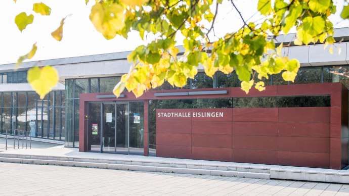 Die Stadthalle Eislingen mit moderner Glasfassade und rotem Eingangsbereich, umgeben von herbstlichen Bl&auml;ttern., &copy; GIACINTO_CARLUCCI