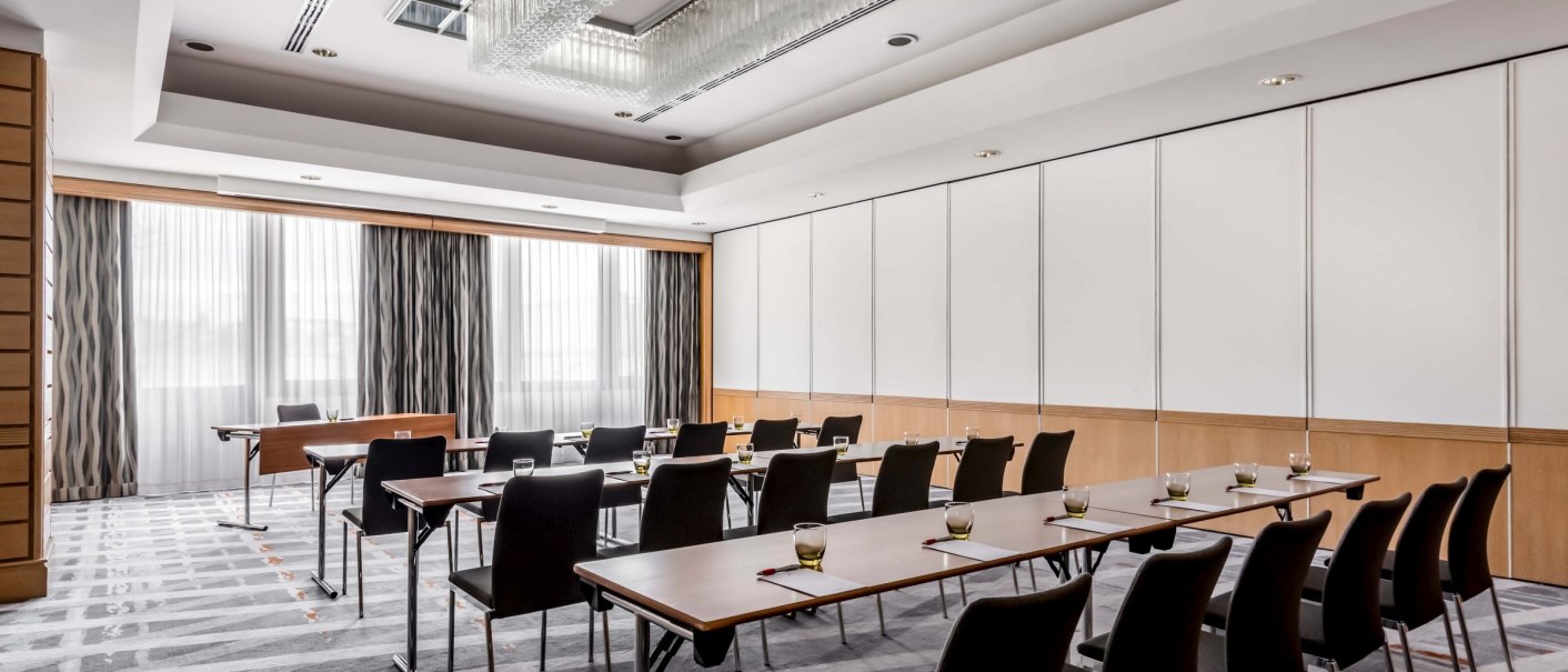 Moderner Konferenzraum mit Tischen und Stühlen, großem Kronleuchter und Tageslicht durch Fenster mit Vorhängen., © Stuttgart Marriott Hotel Sindelfingen, Kilian Blees