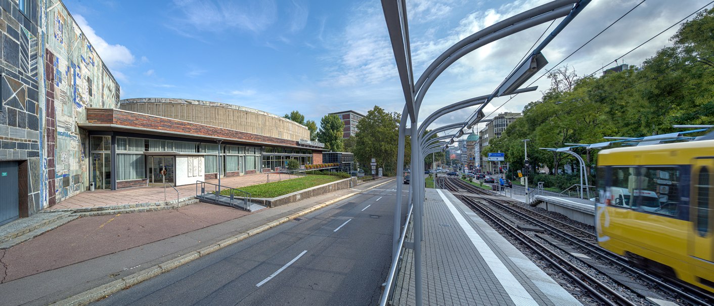 Die Liederhalle mit ihrer markanten Fassade, daneben eine vorbeifahrende gelbe Stra&szlig;enbahn und eine Stra&szlig;e. Im Hintergrund B&auml;ume und Geb&auml;ude., &copy; Kultur- und Kongresszentrum Liederhalle, Florian Selig