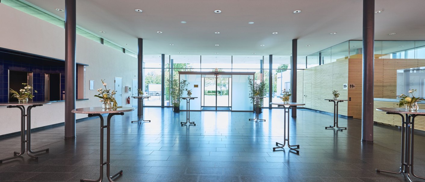 Modern foyer with bar tables, flower vases and a large glass front. Bright, open atmosphere with minimalist furnishings., &copy; bebopmedia lukas breusch