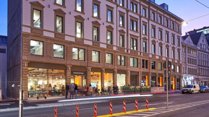 B&uuml;rogeb&auml;ude bei Abendd&auml;mmerung, beleuchtete Fenster, Menschen vor dem Eingang. Moderne Architektur mit klassischer Fassade., &copy; Design Offices