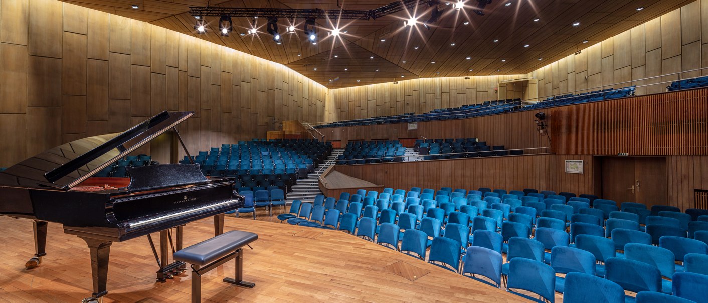 Der Mozart Saal in der Liederhalle mit einem Fl&uuml;gel auf der B&uuml;hne und blauen Sitzreihen. Die W&auml;nde sind holzverkleidet, die Beleuchtung ist warm., &copy; Kultur- und Kongresszentrum Liederhalle, Florian Selig