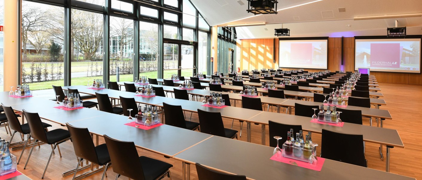 Moderner Konferenzraum mit großen Fenstern, Tischen und Stühlen in Reihen, Präsentationsbildschirmen und Getränken auf den Tischen., © Guenter E. Bergmann - Photography