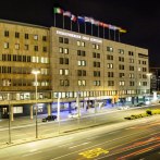 Nachtansicht des Steigenberger Graf Zeppelin Hotels in Stuttgart. Die beleuchtete Fassade zeigt mehrere Fenster und wehende Flaggen auf dem Dach., © Steigenberger Hotels AG, Tanja Ganzer