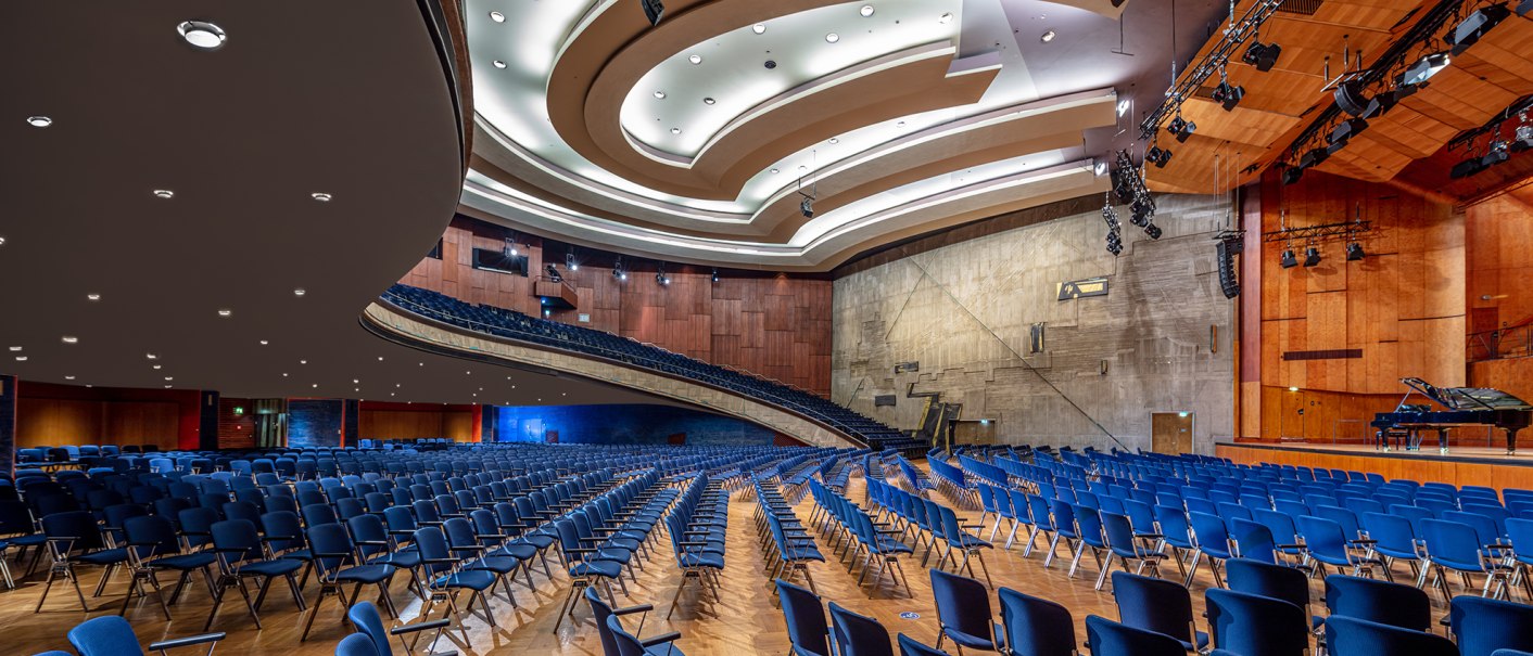 The Beethoven Hall in the Liederhalle with empty blue chairs, a stage with a grand piano and modern ceiling lighting., © Kultur- und Kongresszentrum Liederhalle, Florian Selig The Beethoven Hall in the Liederhalle with empty blue chairs, a stage with a grand piano and modern ceiling lighting., © Kultur- und Kongresszentrum Liederhalle, Florian Selig