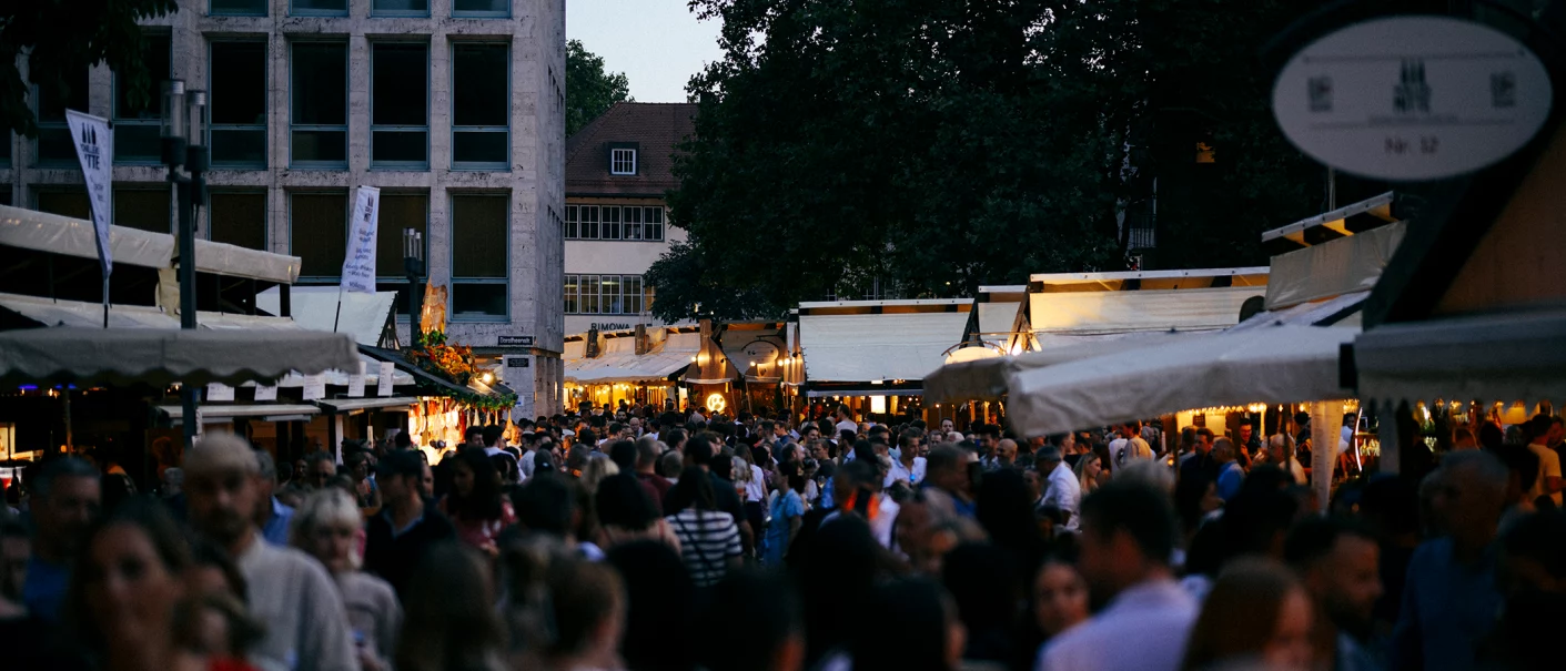 A dense crowd at the Stuttgart Wine Festival in 2025, surrounded by illuminated booths at dusk., &copy; Pro Stuttgart e.V.