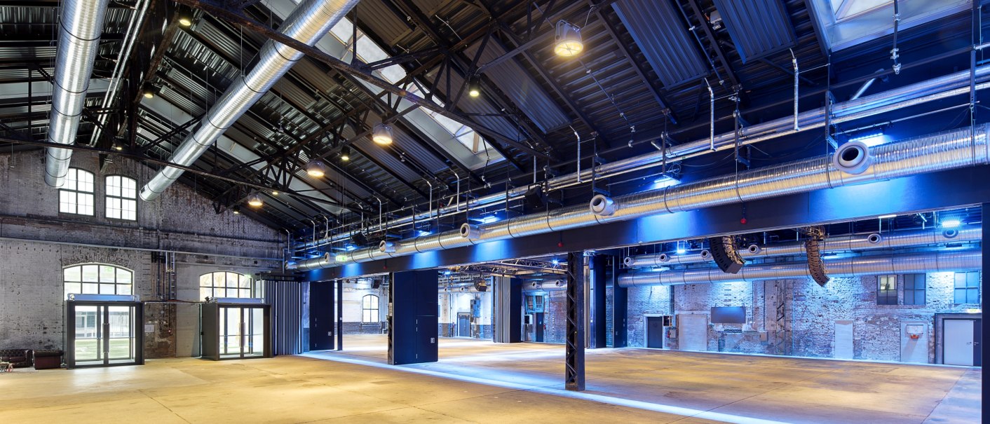 Large hall with industrial design, visible pipes and blue lighting. High ceiling with metal beams and large windows., &copy; Wagenhallen Stuttgart GmbH & Co. KG