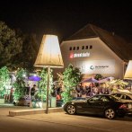 Die Phoenixhalle im Römerkastell bei Nacht, mit beleuchtetem Außenbereich, Pflanzen und geparkten Autos. Menschen genießen die Atmosphäre., © Julian Rettig