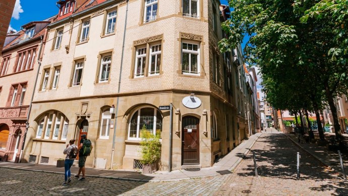 Historische Gebäude im Bohnenviertel mit Kopfsteinpflasterstraße und Bäumen. Zwei Personen spazieren entlang der Brennerstraße., © Thmoas Niedermüller Historische Gebäude im Bohnenviertel mit Kopfsteinpflasterstraße und Bäumen. Zwei Personen spazieren entlang der Brennerstraße., © Thmoas Niedermüller