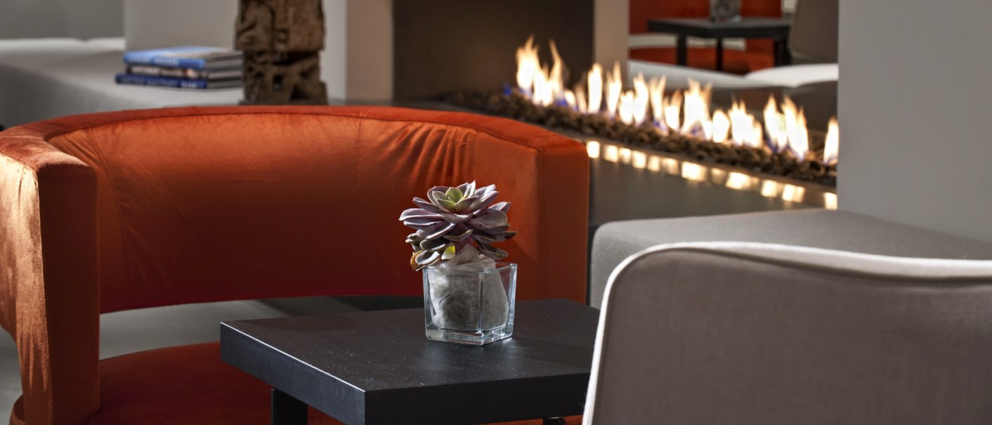 Modern lobby with red armchair, table with plant, open fire and decorative sculptures in the background., &copy; Wyndham Stuttgart Airport Messe