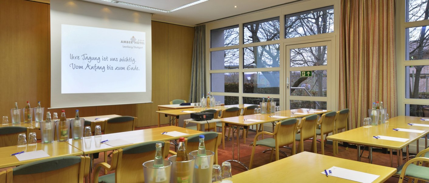 Meeting room at the Amber Hotel Leonberg/Stuttgart with tables, chairs, water bottles and a presentation screen., &copy; DH STUDIO Dirk Holst