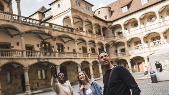 Three people stand in the inner courtyard of the Württemberg State Museum and look upwards. The inner courtyard is surrounded by arcades and historic buildings., © Stuttgart-Marketing GmbH, wpsteinheisser Three people stand in the inner courtyard of the Württemberg State Museum and look upwards. The inner courtyard is surrounded by arcades and historic buildings., © Stuttgart-Marketing GmbH, wpsteinheisser