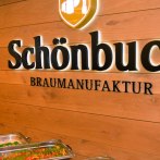 Interior view of a brewery with buffet. "Sch&ouml;nbuch Braumanufaktur" is written on the wooden wall. In the foreground are dishes in warming containers., &copy; &copy; Sch&ouml;nbuchbrauerei, Sebastian Berger
