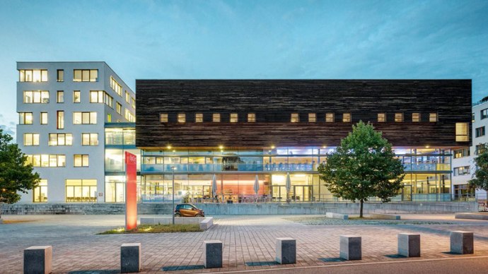 Modern architecture of SpOrt Stuttgart at dusk, with illuminated windows and a tree in the foreground., &copy; &copy; 2016 by Josh von Staudach